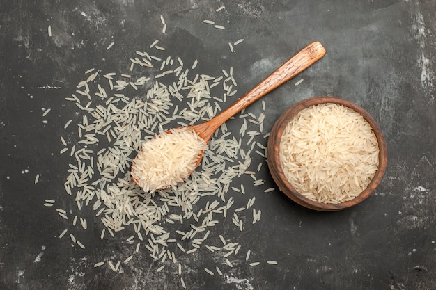 Vista superior de longe arroz arroz na colher e tigela na mesa escura
