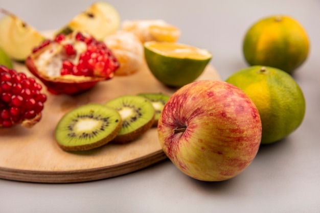 Vista superior de maçãs frescas com frutas, como maçãs kiwi com romã, em uma placa de cozinha de madeira