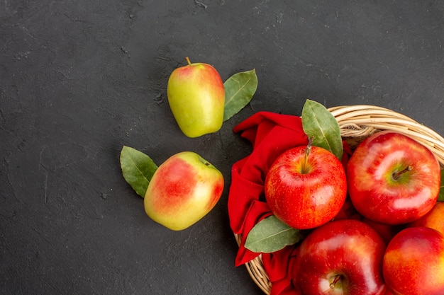 Vista superior de maçãs frescas com pêssegos dentro de uma cesta em piso escuro com frutas maduras frescas