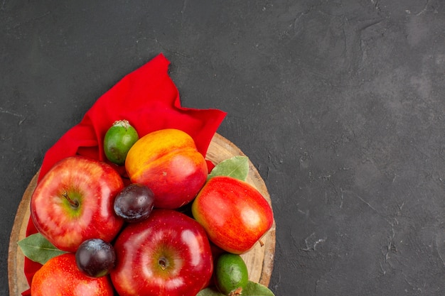 Vista superior de maçãs frescas com pêssegos e ameixas em um suco suave de árvore frutífera de mesa escura