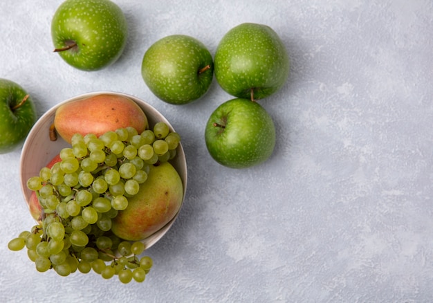 Foto grátis vista superior de maçãs verdes com uvas verdes e peras em uma tigela em um fundo branco