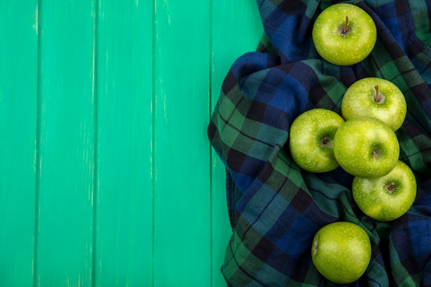 Vista superior de maçãs verdes em pano xadrez na superfície verde