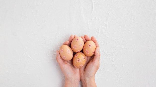 Vista superior de mãos segurando ovos de páscoa decorados