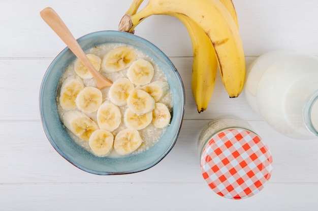 Vista superior de mingau de aveia com banana em uma tigela de cerâmica na mesa rústica