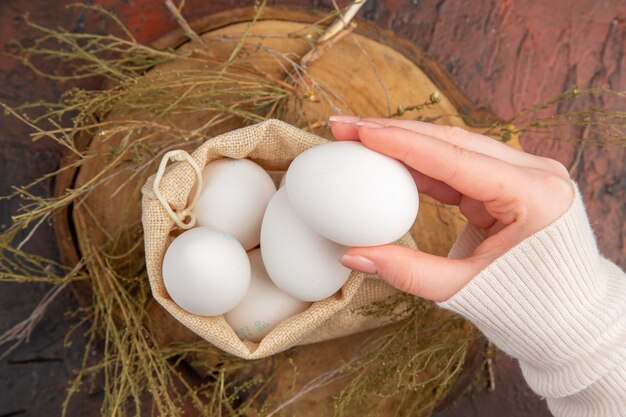 Vista superior de ovos de galinha dentro de uma sacolinha com mão feminina