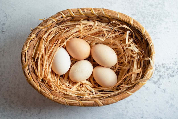 Vista superior de ovos de galinha orgânicos na cesta sobre uma superfície cinza.