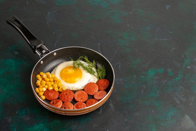 Foto grátis vista superior de ovos mexidos com salsichas fatiadas e verduras dentro da panela no fundo escuro