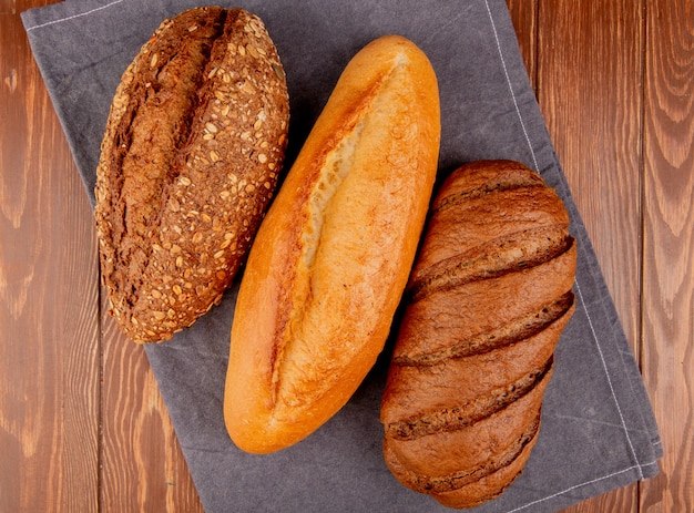 vista superior de pães como baguete de sementes vietnamita e preta e pão preto em pano cinza e mesa de madeira