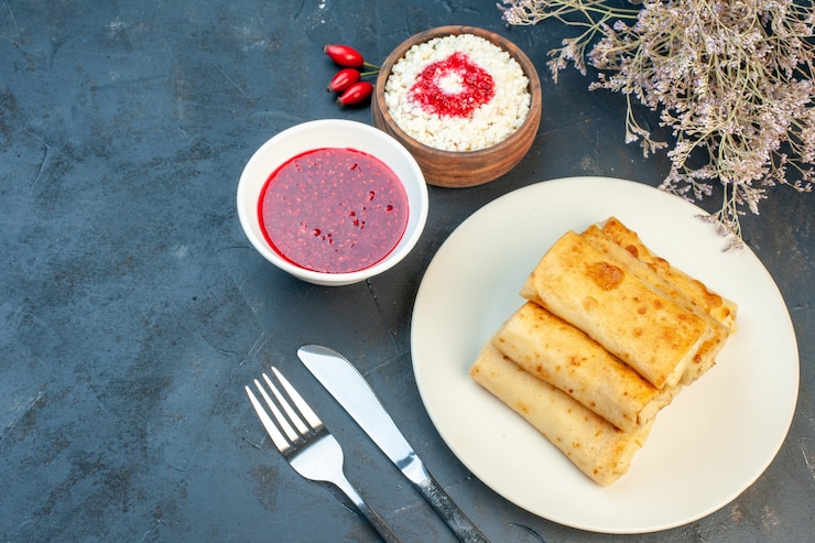 Foto grátis vista superior de panos de lavash em um prato e conjunto de talheres com queijo ralado no lado esquerdo em fundo preto