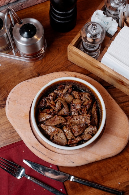 Foto grátis vista superior de pedaços de carne frita em uma tigela de barro com especiarias em uma placa de madeira