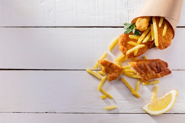 Vista superior de peixe e batatas fritas em cone de papel com espaço de cópia