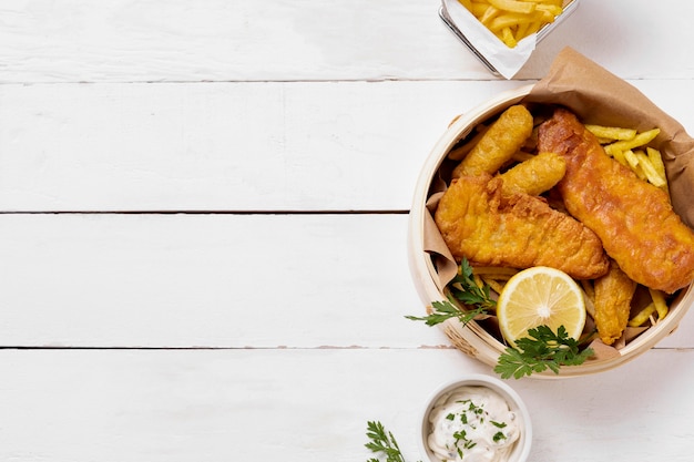 Vista superior de peixe e batatas fritas em uma tigela com limão