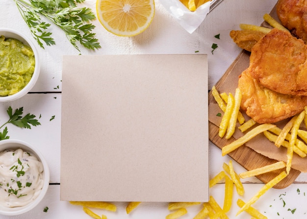 Vista superior de peixe e batatas fritas na tábua de cortar com cartão