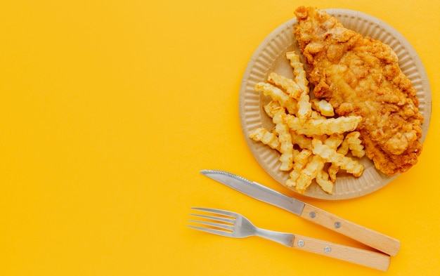 Foto grátis vista superior de peixe e batatas fritas no prato com talheres