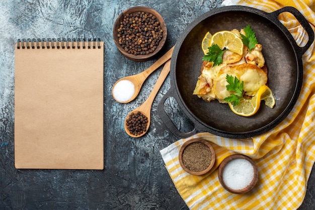 Vista superior de peixe frito em uma panela com limão e salsa em uma toalha de mesa quadriculada branca e amarela