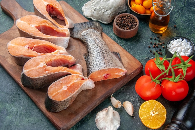 Vista superior de peixes crus frescos em alimentos frescos de garrafa de óleo de tábua de madeira na mesa de mistura de cores escuras