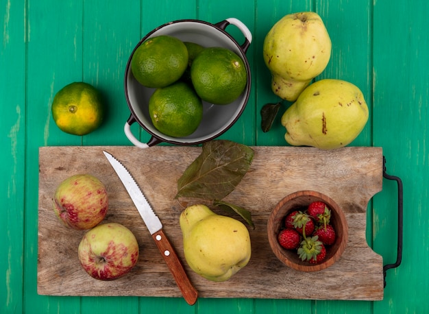 Vista superior de peras com maçãs, tangerinas e morangos em uma tábua de cortar