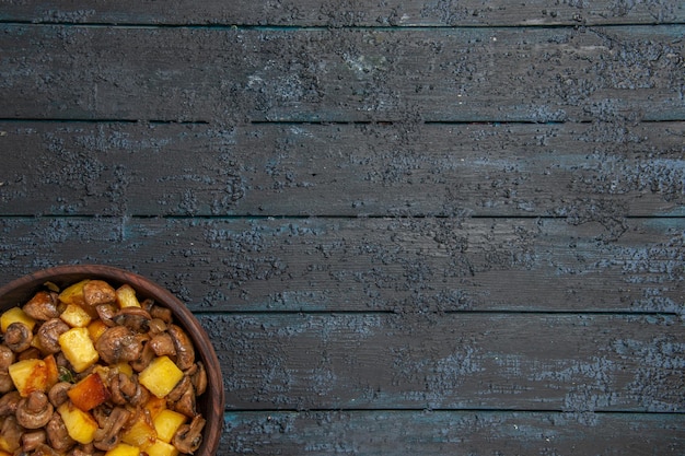 Vista superior de perto tigela de batatas e cogumelos com batatas e cogumelos na parte inferior esquerda da mesa