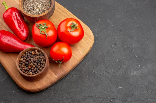 Vista superior de perto tomates vermelhos frescos com temperos no espaço escuro