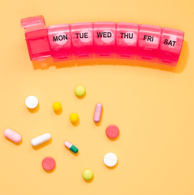 Vista superior de pílulas e recipiente com dias das semanas