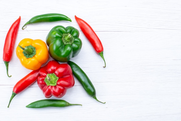 Foto grátis vista superior de pimentões cheios de pimenta com pimentas picantes na mesa branca, produto de ingrediente de refeição quente de tempero vegetal