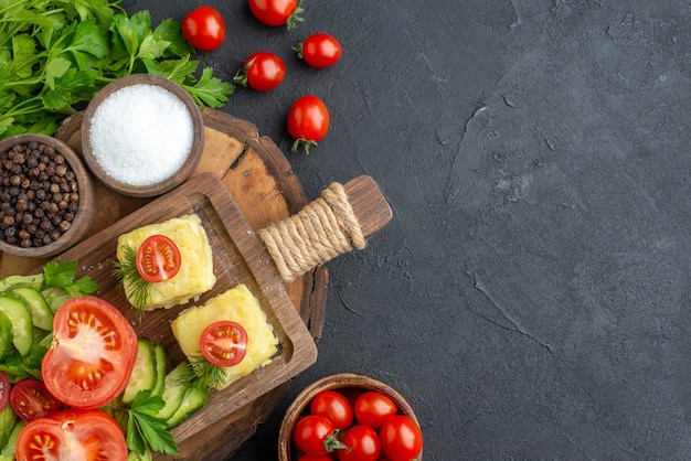 Vista superior de queijo de legumes frescos picados na tábua e pacote de especiarias verdes no lado direito na superfície preta