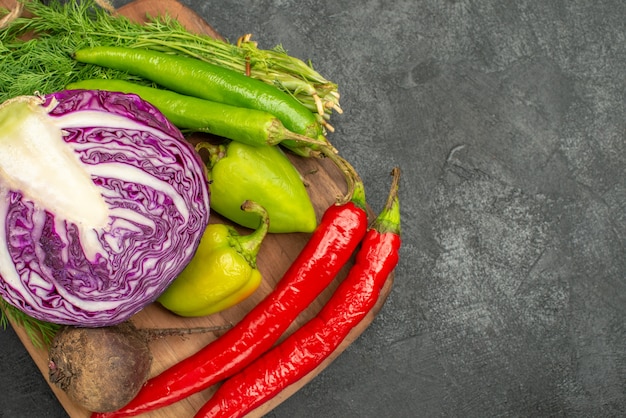 Vista superior de repolho roxo fatiado com outros vegetais em fundo escuro