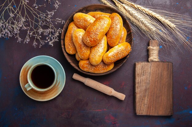 Vista superior de rissóis doces com uma xícara de chá no fundo escuro Massa de pastelaria refeição comida rissóis chá