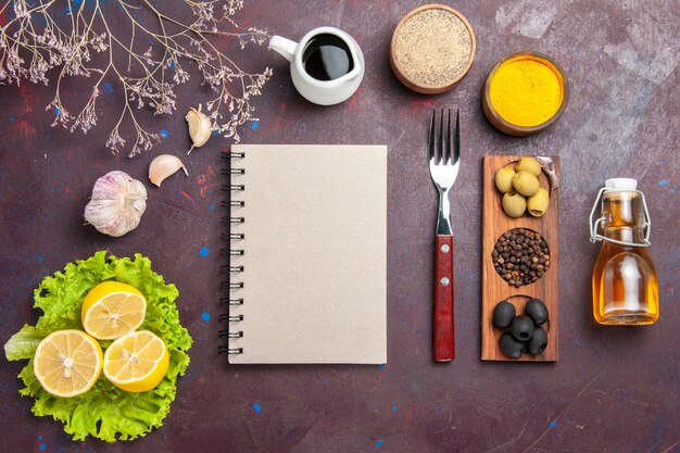 Vista superior de rodelas de limão frescas com salada verde e azeitonas no escuro