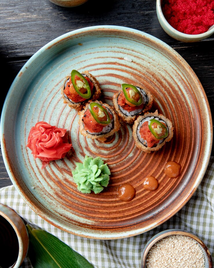 Foto grátis vista superior de rolos de sushi fritos com wasabi e gengibre em um prato em madeira