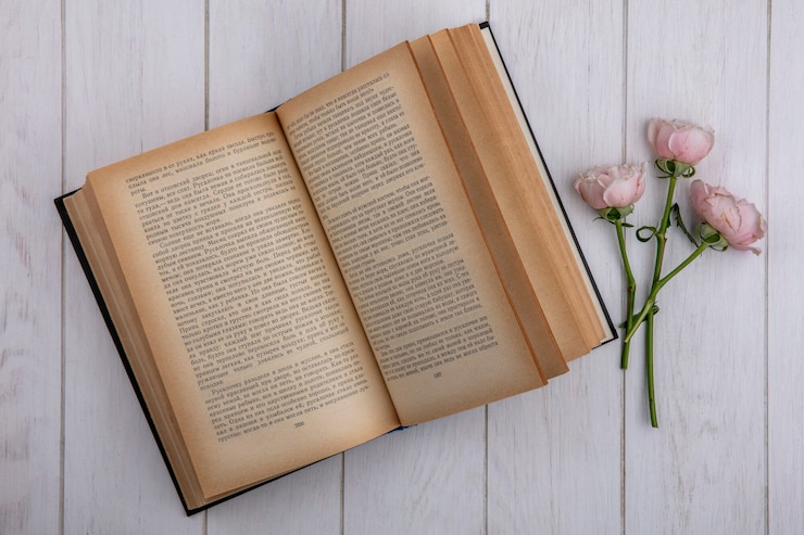 Foto grátis vista superior de rosas rosa claras com um livro aberto em uma superfície cinza