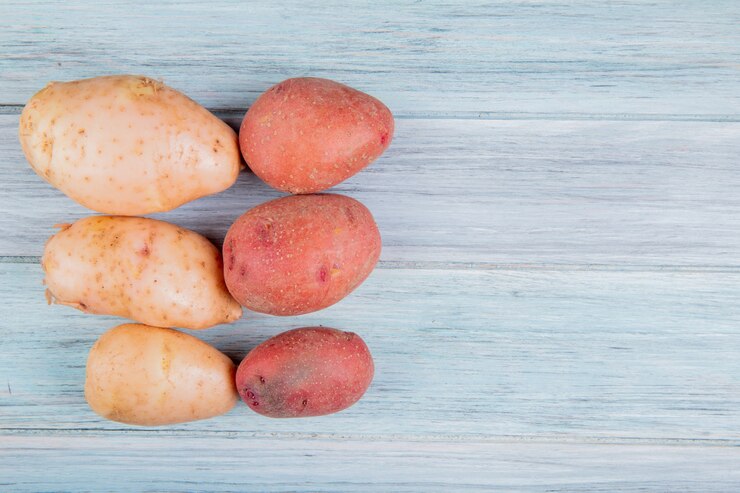 Foto grátis vista superior de russet e batatas vermelhas no lado esquerdo e superfície de madeira com espaço de cópia