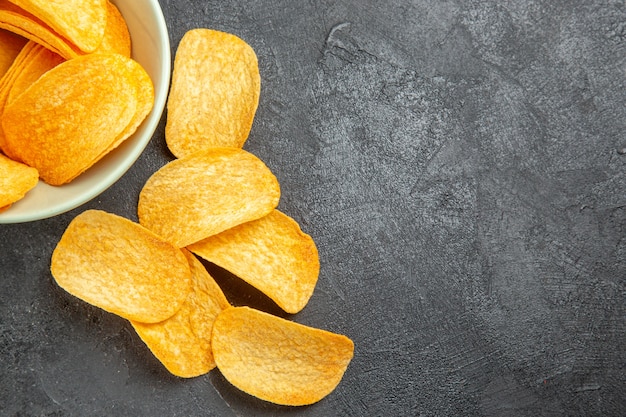 Foto grátis vista superior de saborosos chips de queijo dentro do prato em fundo escuro