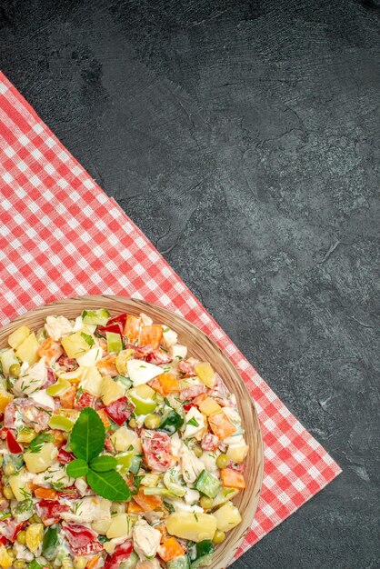 Vista superior de salada de legumes em uma tigela no guardanapo vermelho sobre fundo cinza escuro