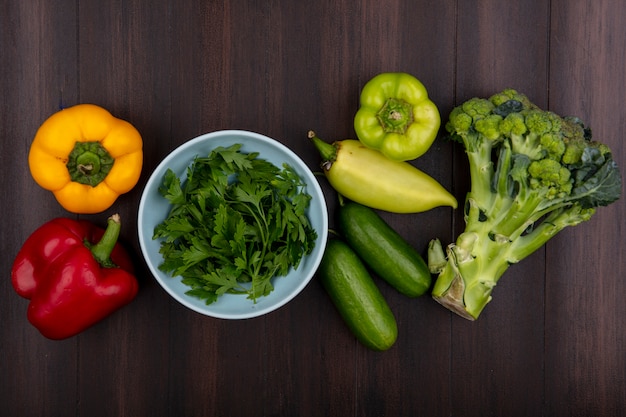 Vista superior de salsa em uma tigela com pepino brócolis e pimentão em um fundo de madeira