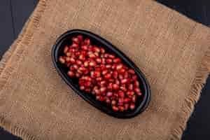 Foto grátis vista superior de sementes de romã vermelha em uma placa preta na superfície do pano de saco