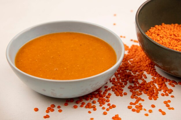 Vista superior de sopa de lentilha saudável em uma tigela com lentilhas frescas isoladas em uma superfície branca