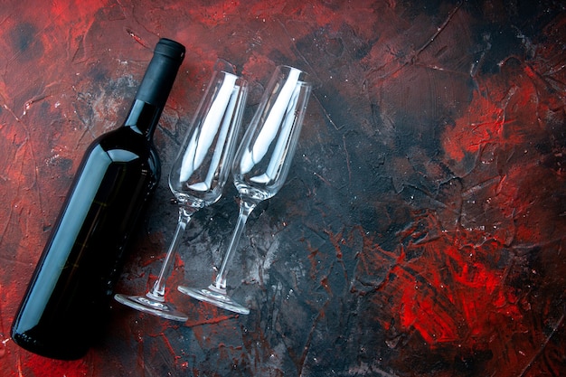 Vista superior de taças de vinho vazias com garrafa de vinho em fundo escuro