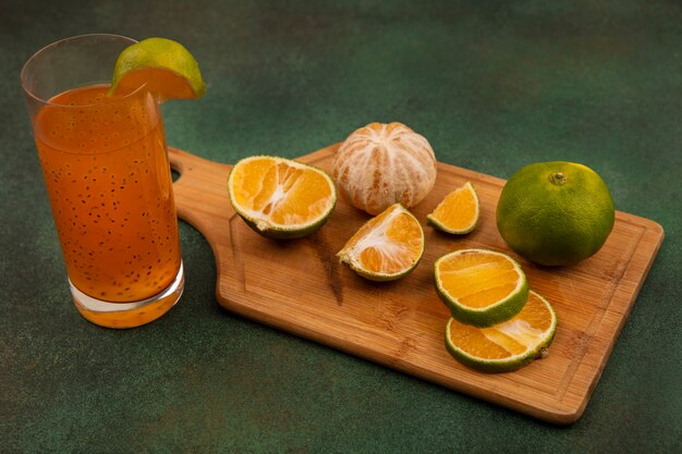 Vista superior de tangerinas frescas abertas e picadas em uma placa de cozinha de madeira com suco de frutas frescas em um copo