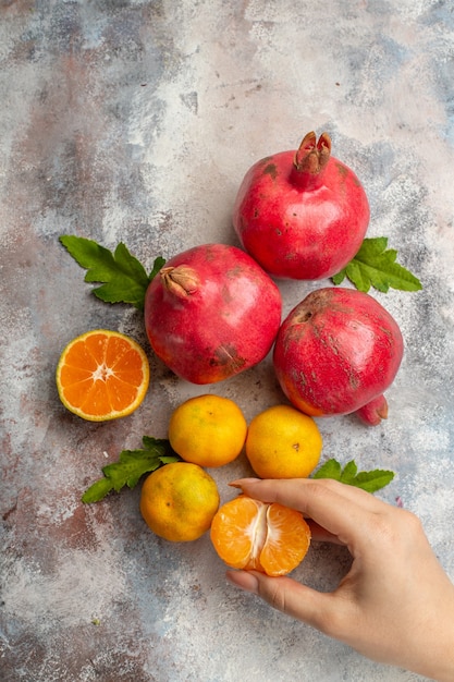 Vista superior de tangerinas frescas com romãs vermelhas em fundo claro