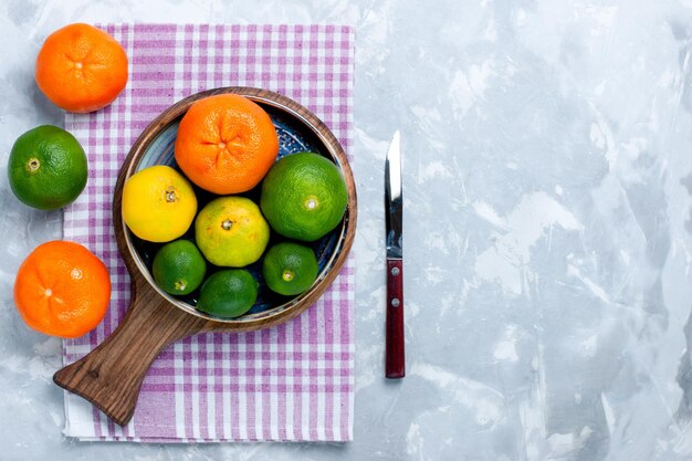 Vista superior de tangerinas frescas e ácidas com limões na mesa branca clara