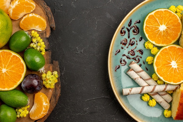 Vista superior de tangerinas verdes frescas com feijoas e fatias de bolo no escuro