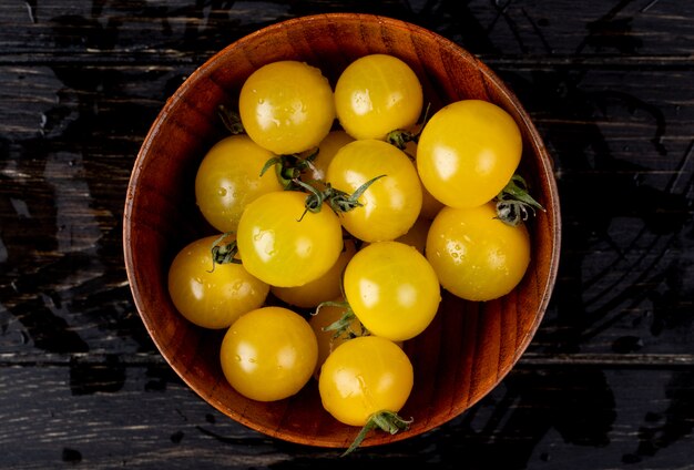 Vista superior de tomates amarelos em tigela na mesa de madeira