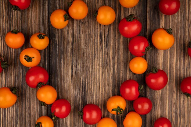 Vista superior de tomates cereja orgânicos vermelhos e laranja isolados em uma parede de madeira com espaço de cópia