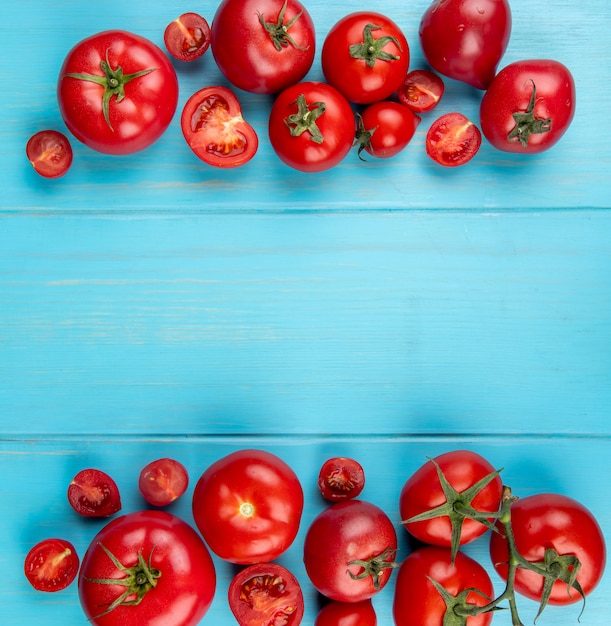 Vista superior de tomates cortados e inteiros na superfície azul com espaço de cópia