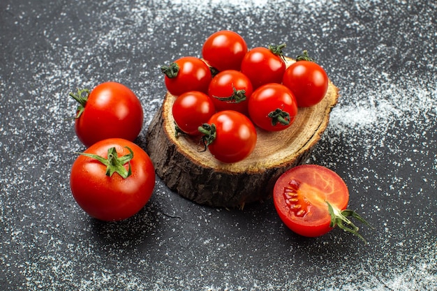 Vista superior de tomates frescos com caules na placa de madeira e em fundo preto wite