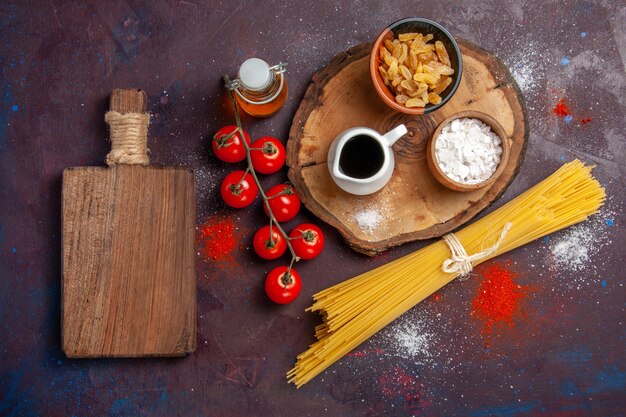 Vista superior de tomates vermelhos frescos com passas e massa crua em fundo escuro Salada de refeição