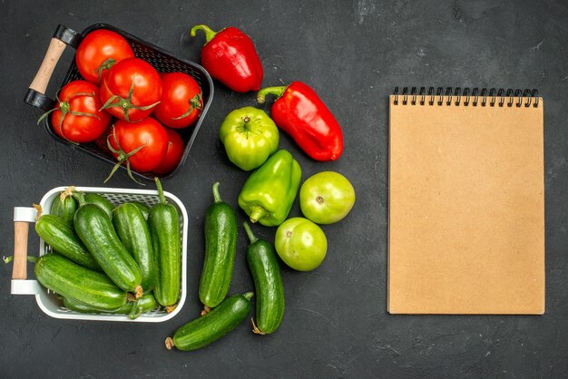 Vista superior de tomates vermelhos frescos com pepinos na mesa escura