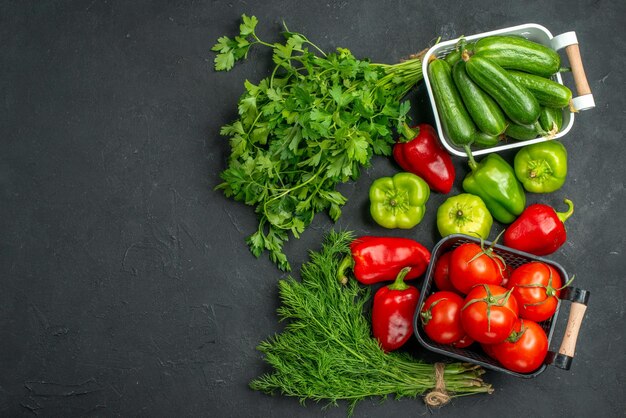 Vista superior de tomates vermelhos frescos com verduras e pimentões em fundo escuro