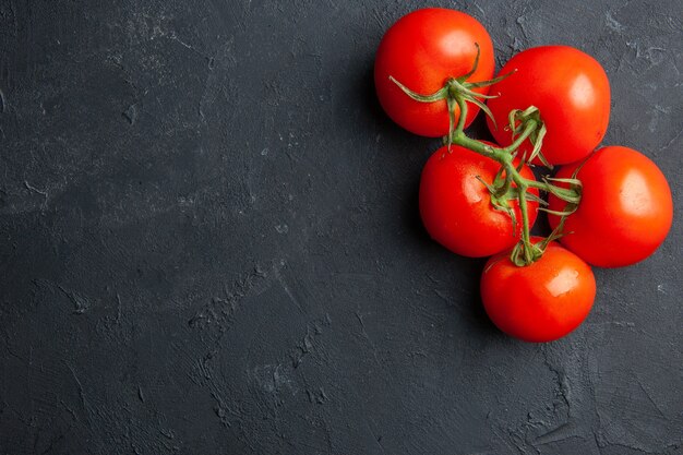 Vista superior de tomates vermelhos frescos em fundo escuro